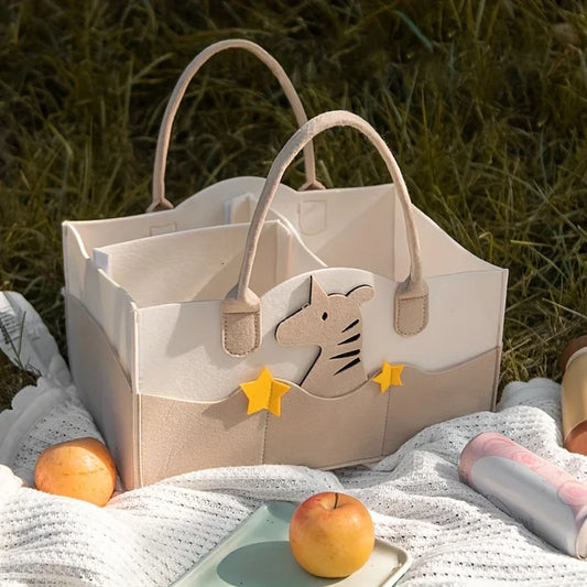 Beige tote caddy bag with zebra design on grass with apples and a blanket